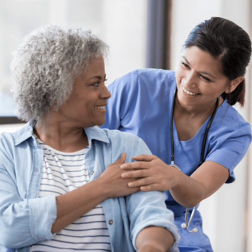 Female nurse smiling with older female patient